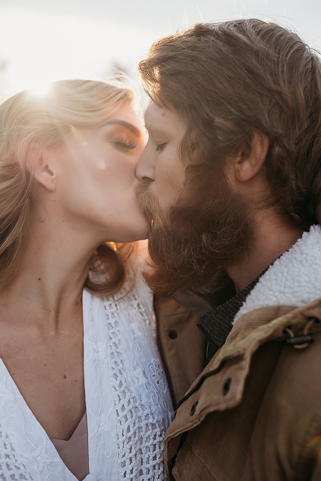 Engaged couple kissing at sunset